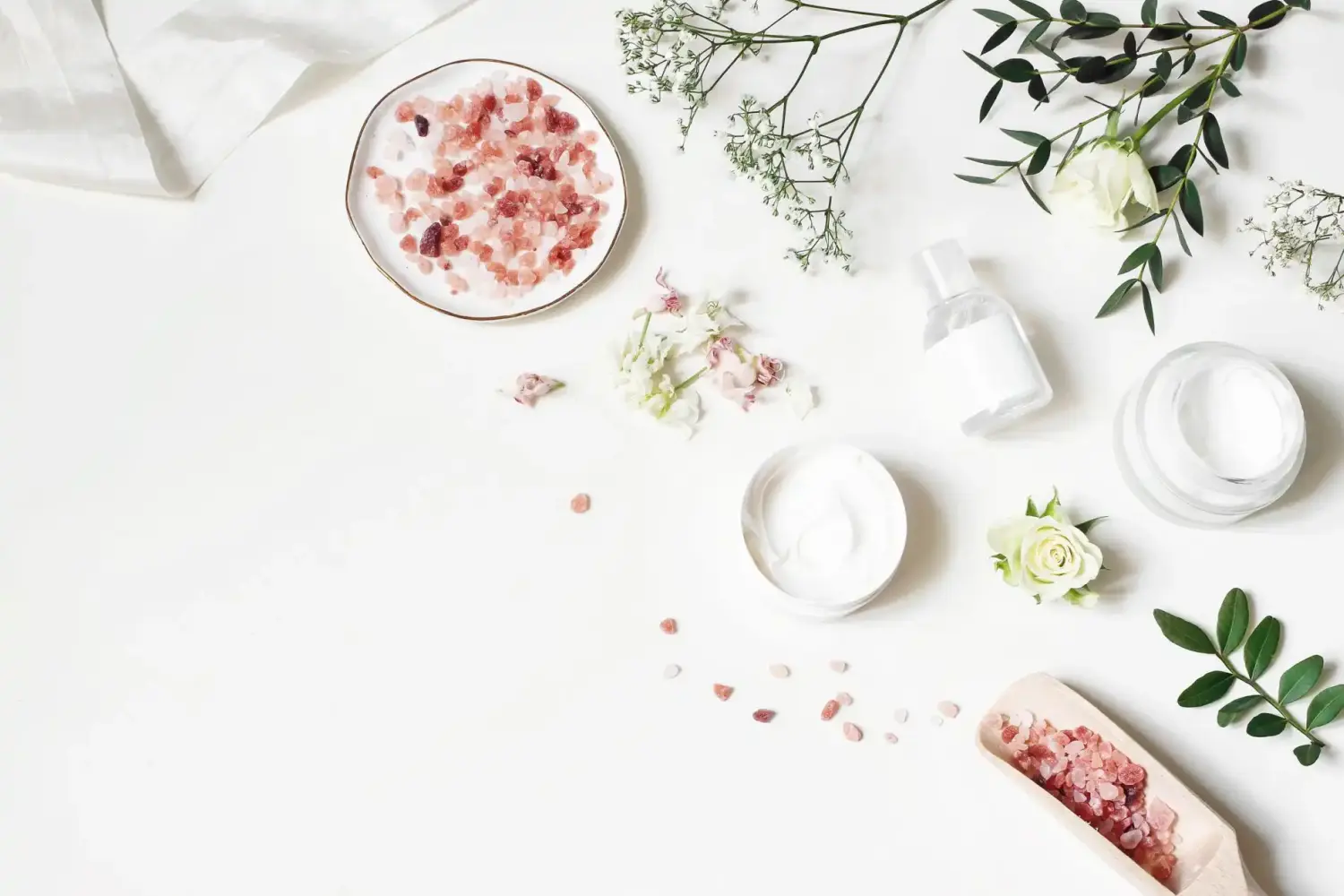 Hautcreme, Tonicum-Flasche, Trockenblumen, Blätter, Rose und Himalaya-Salz. Weißer Tischhintergrund